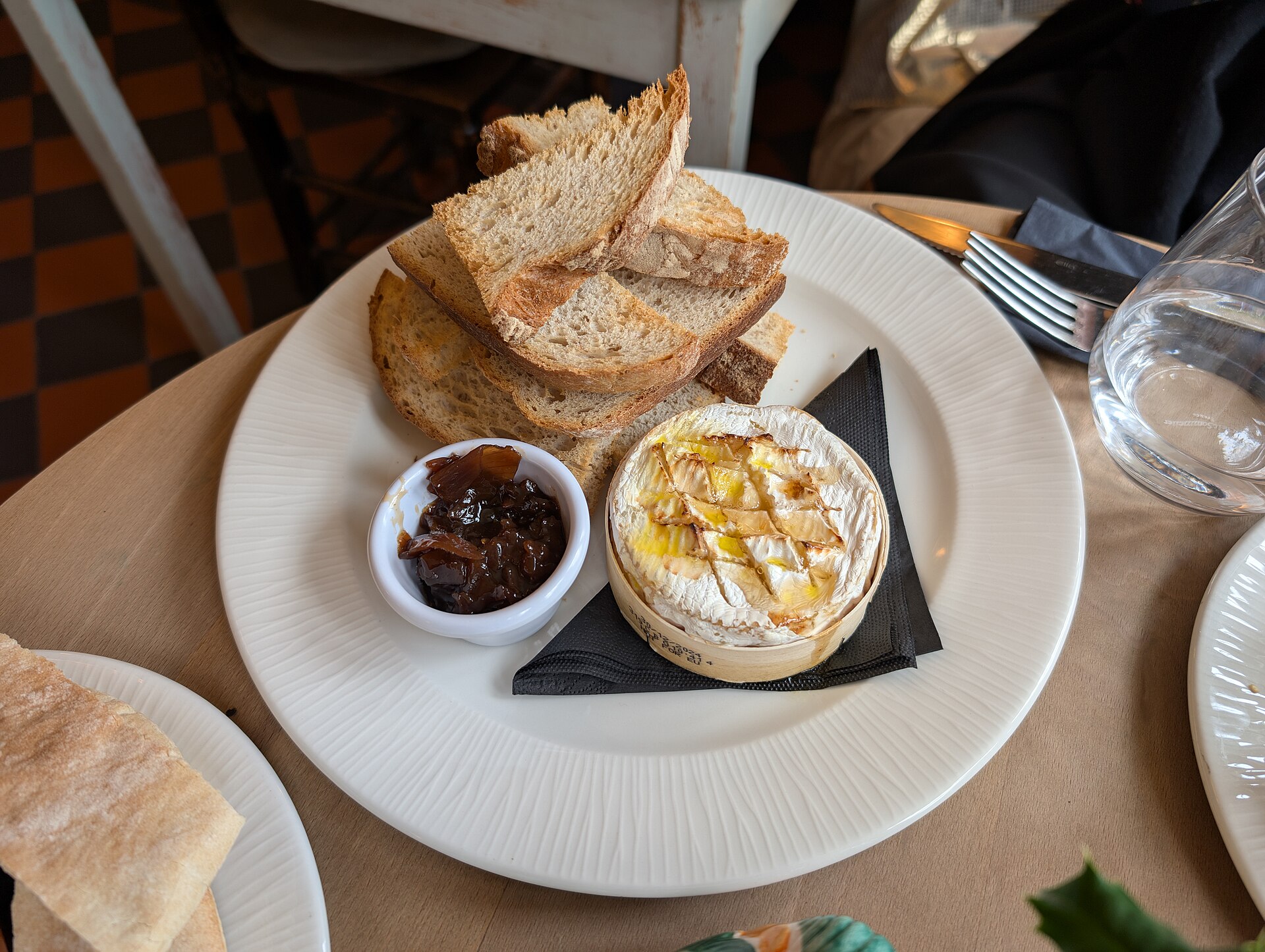 Baked brie wheel on a plate with toast and chutney